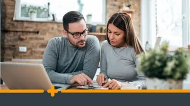 Zamartwiona para omawia formalności finansowe przy komputerze